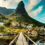 Odkryj malowniczy krajobraz Vågan w Nordland ze wspaniałym drewnianym mostem prowadzącym do kolorowych domów.