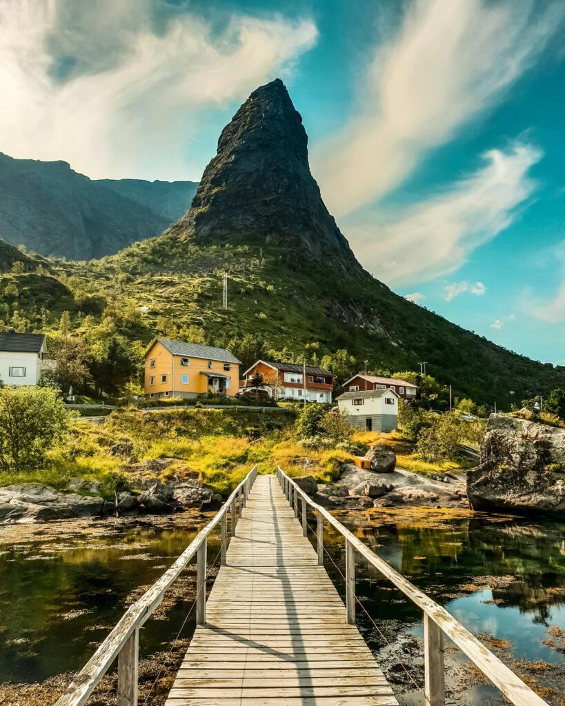 Odkryj malowniczy krajobraz Vågan w Nordland ze wspaniałym drewnianym mostem prowadzącym do kolorowych domów.