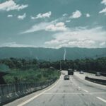 Malownicza autostrada jadąca przez górską scenerię pod jasnym błękitnym niebem.