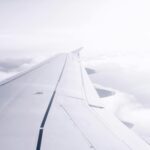 Spokojny widok skrzydła samolotu lecącego nad chmurami, uchwycony esencją podróży