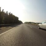 Biały samochód podróżujący po czystej autostradzie w Hatfield w Anglii z malowniczymi drzewami.