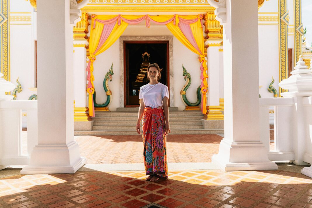 podroz Kobieta stoi przy tętniącym życiem wejściu do świątyni w Krabi w Tajlandii, ozdobionym kolorowymi draperiami i architekturą.