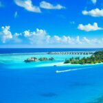 Widok z lotu ptaka na luksusowy tropikalny kurort na dziewiczej wyspie otoczonej lazurowymi wodami i bujną zielenią.