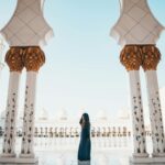 Osoba w tradycyjnym stroju stojąca wśród kolumn meczetu Szejka Zayeda w Abu Zabi.