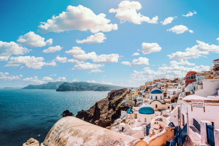 Urzekający widok na słynne budynki z niebieskimi kopułami Santorini pod tętniącym życiem niebem.