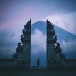 Sylwetka w świątyni Pura Lempuyang na Bali z górą Agung w tle o zmierzchu.