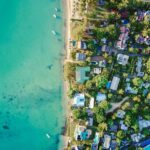 Oszałamiający widok z lotu ptaka na tętniącą życiem tropikalną przybrzeżną wioskę z turkusowymi wodami i bujną zielenią.