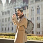 Fakty i mity o „życiu jak w filmie podróżniczym” Turysta robiący zdjęcia przed budynkiem parlamentu w Budapeszcie na Węgrzech.