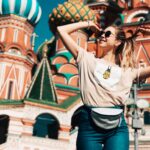 Fakty i mity o podróżowaniu w pandemii Szczęśliwa kobieta pozuje przed katedrą św. Bazylego w Moskwie, w słoneczny dzień.