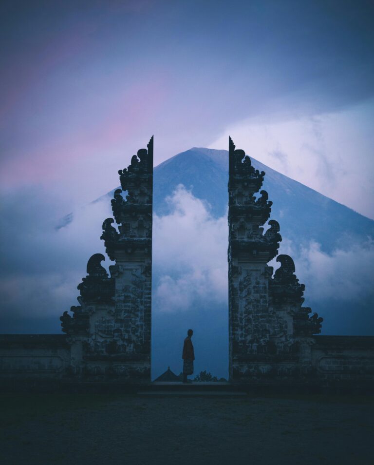 Sylwetka w świątyni Pura Lempuyang na Bali z górą Agung w tle o zmierzchu.