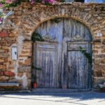 Historyczny kamienny łuk z drewnianymi drzwiami w słonecznej Sardynii, Włochy.