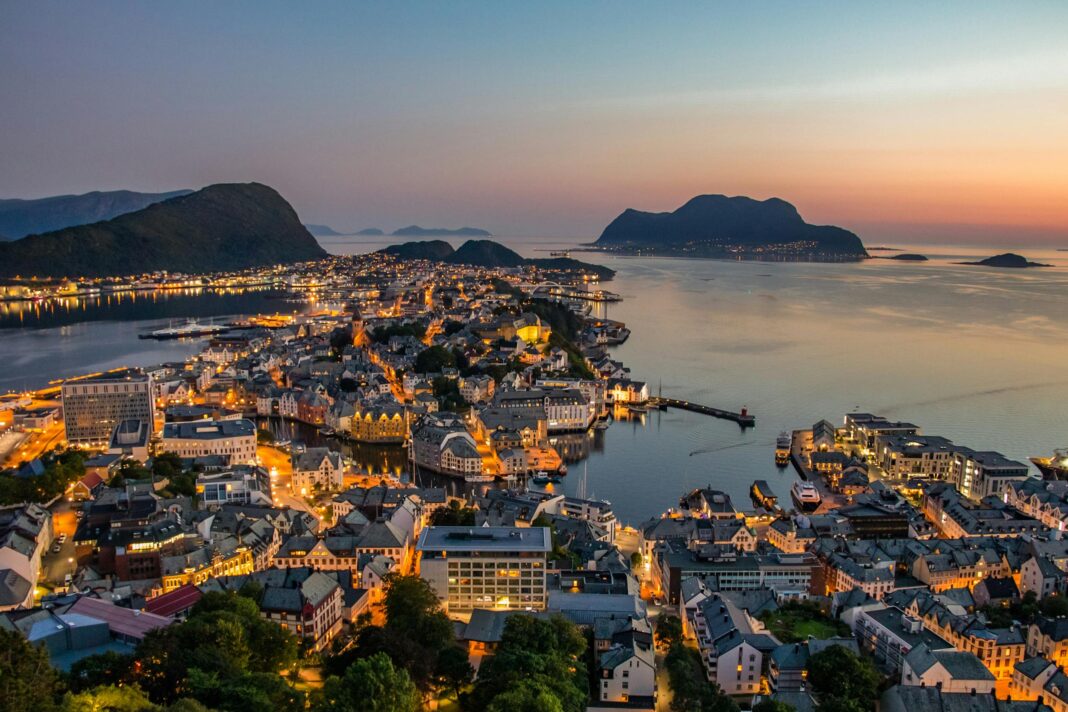 Odkryj zapierającą dech w piersiach panoramę Ålesund w Norwegii, oświetloną na tle oszałamiającego zachodu słońca nad portem.