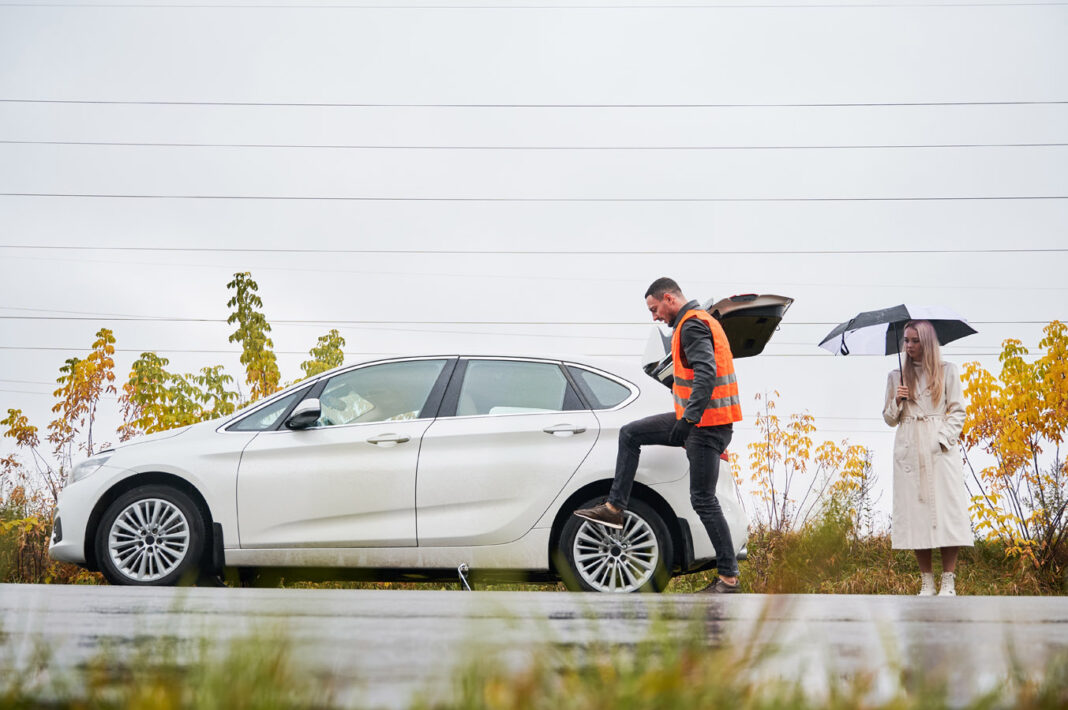 Emergency mechanic repairing woman car on the street.