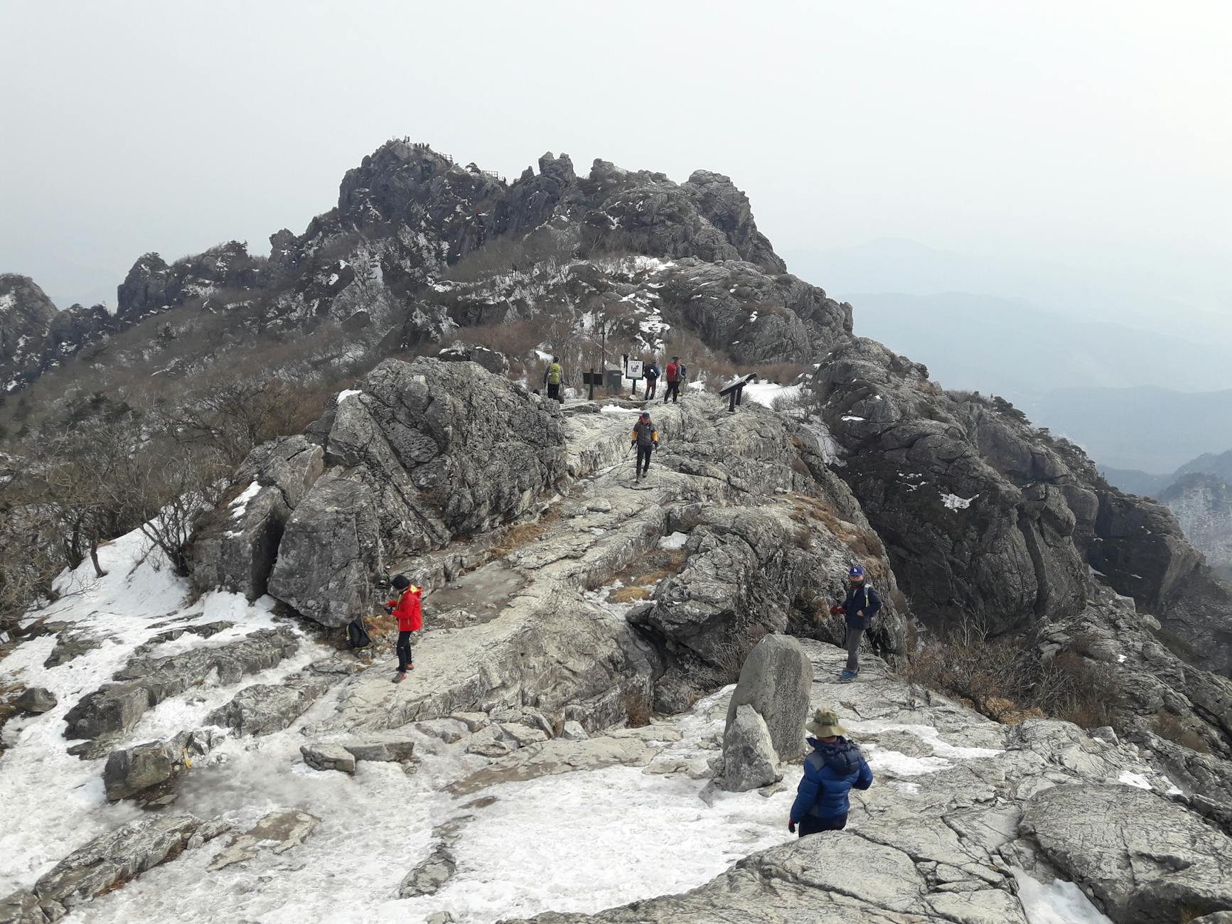 Turyści wspinający się zimą po ośnieżonej, skalistej górze w Hapcheon