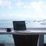 Laptop i kubek kawy na plażowym biurku w Bali, idealne miejsce na workation
