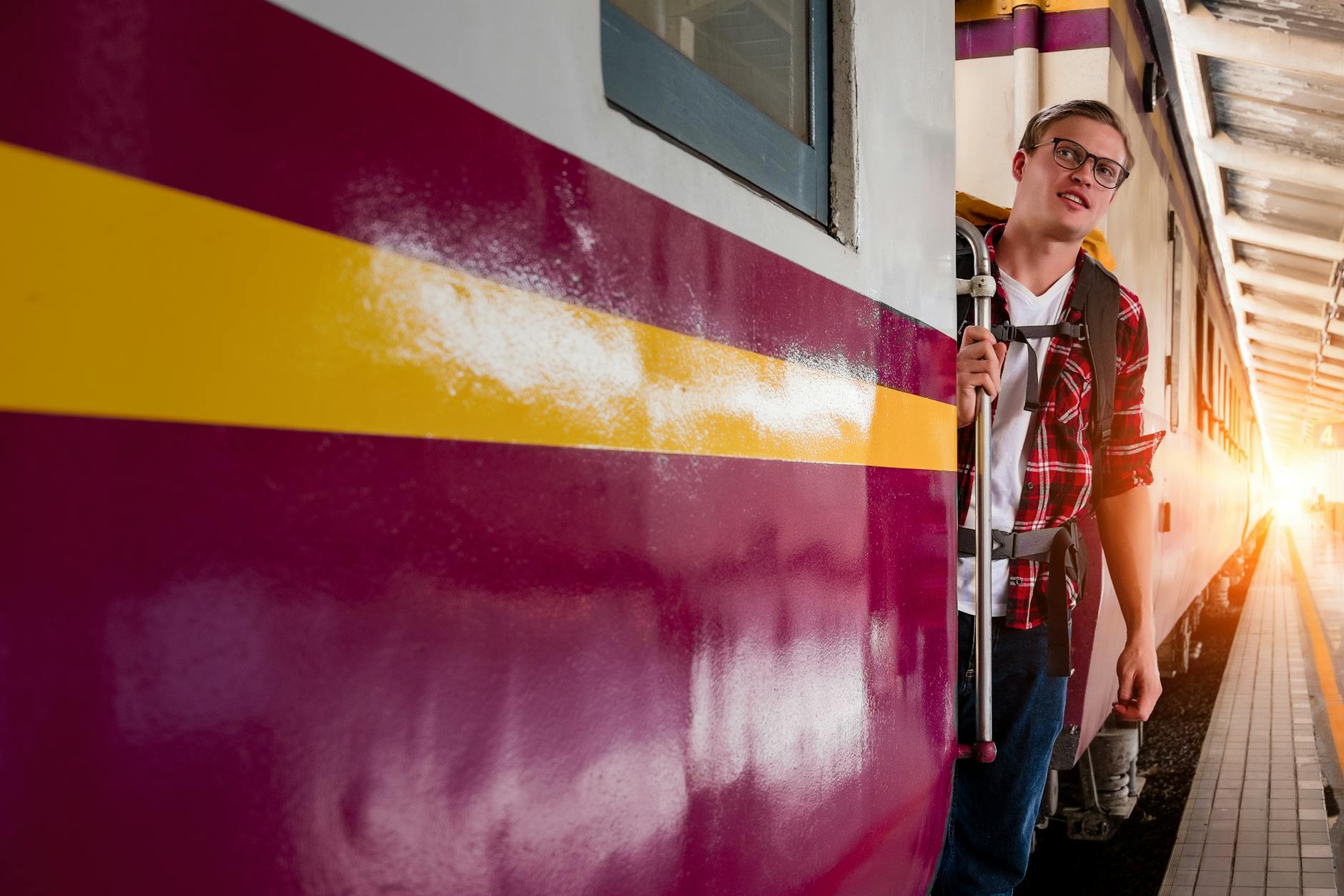 Młody podróżnik z plecakiem wsiada do pociągu na miejskiej stacji