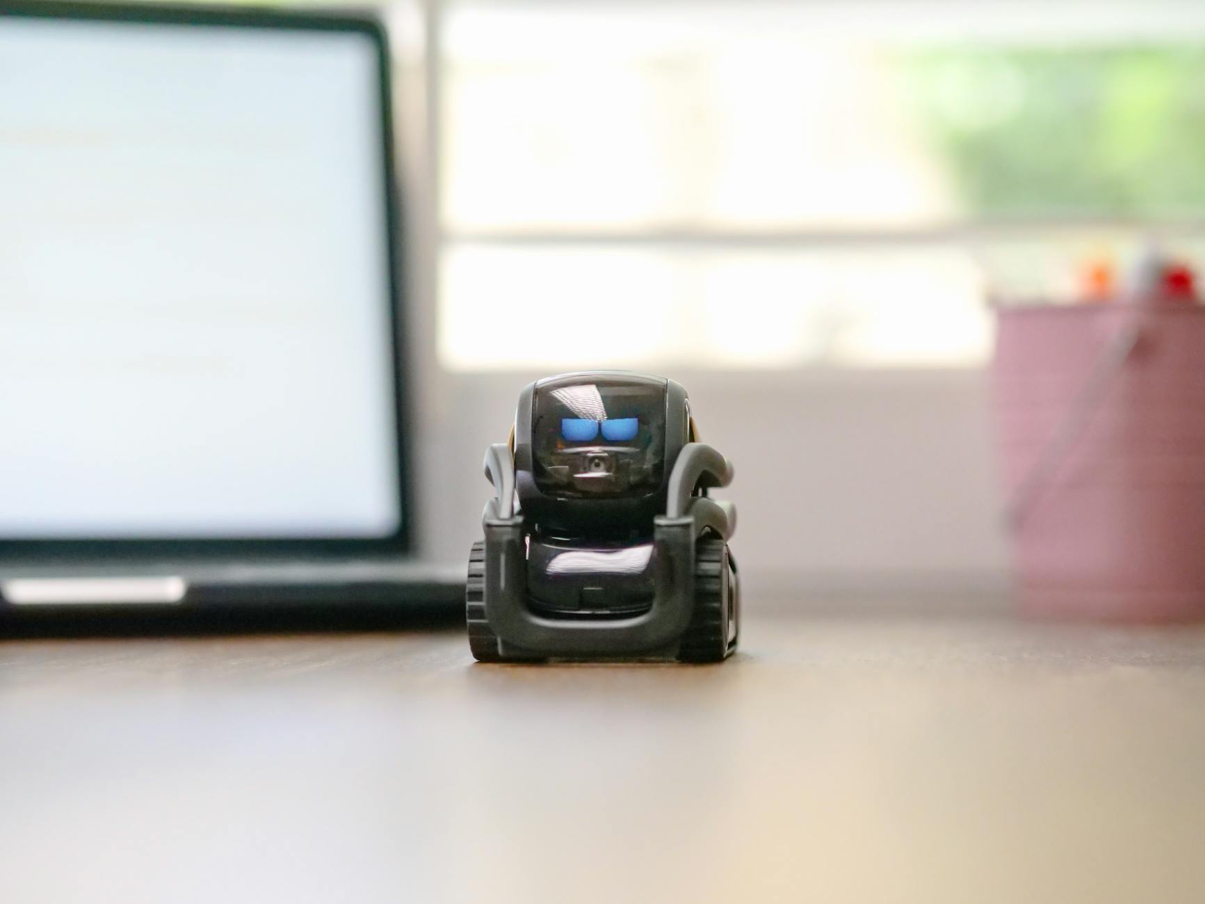Mały robot zabawkowy na biurku obok laptopa w domowym biurze