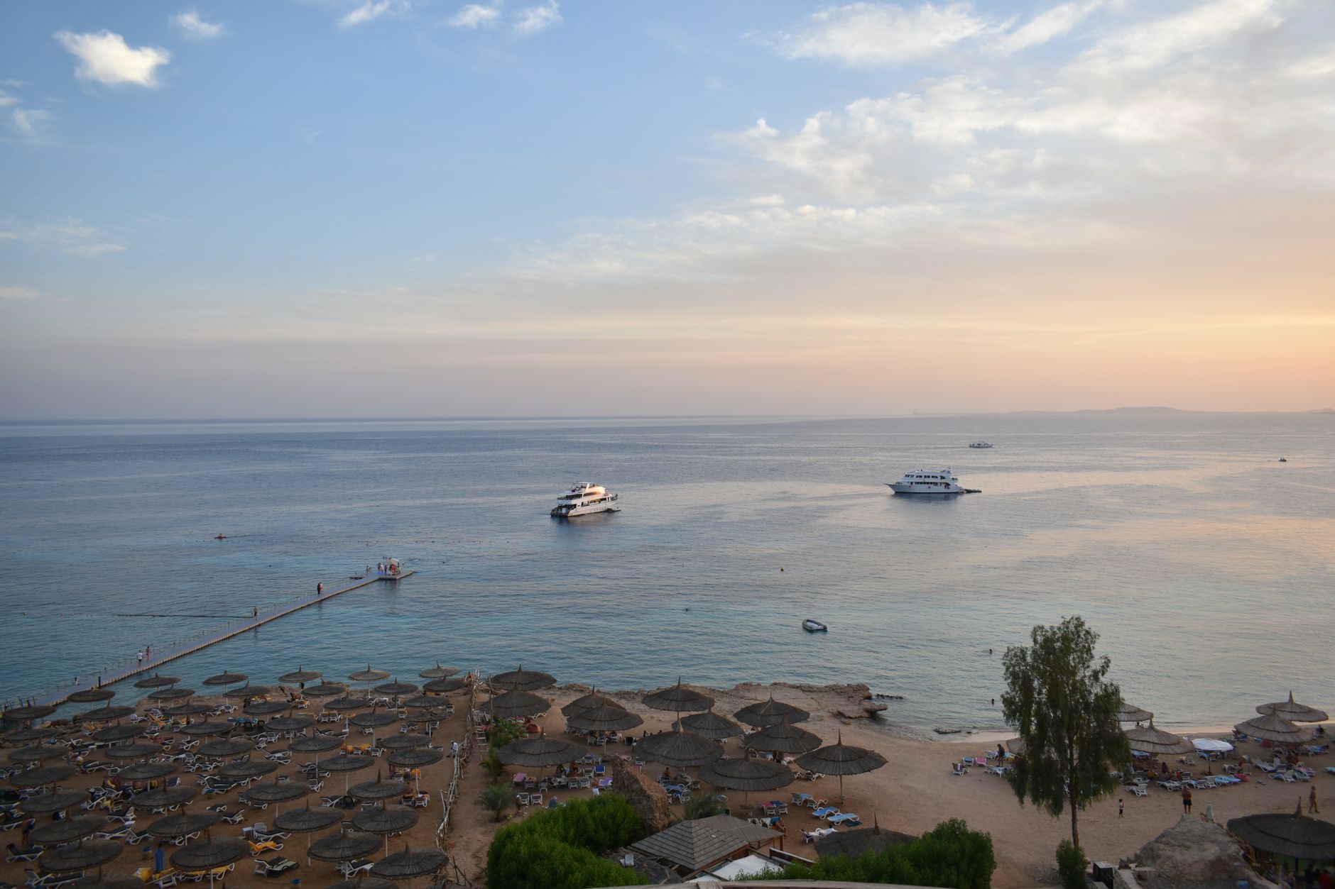 Plaża w Sharm El Sheikh o zachodzie słońca z łódkami i parasolami