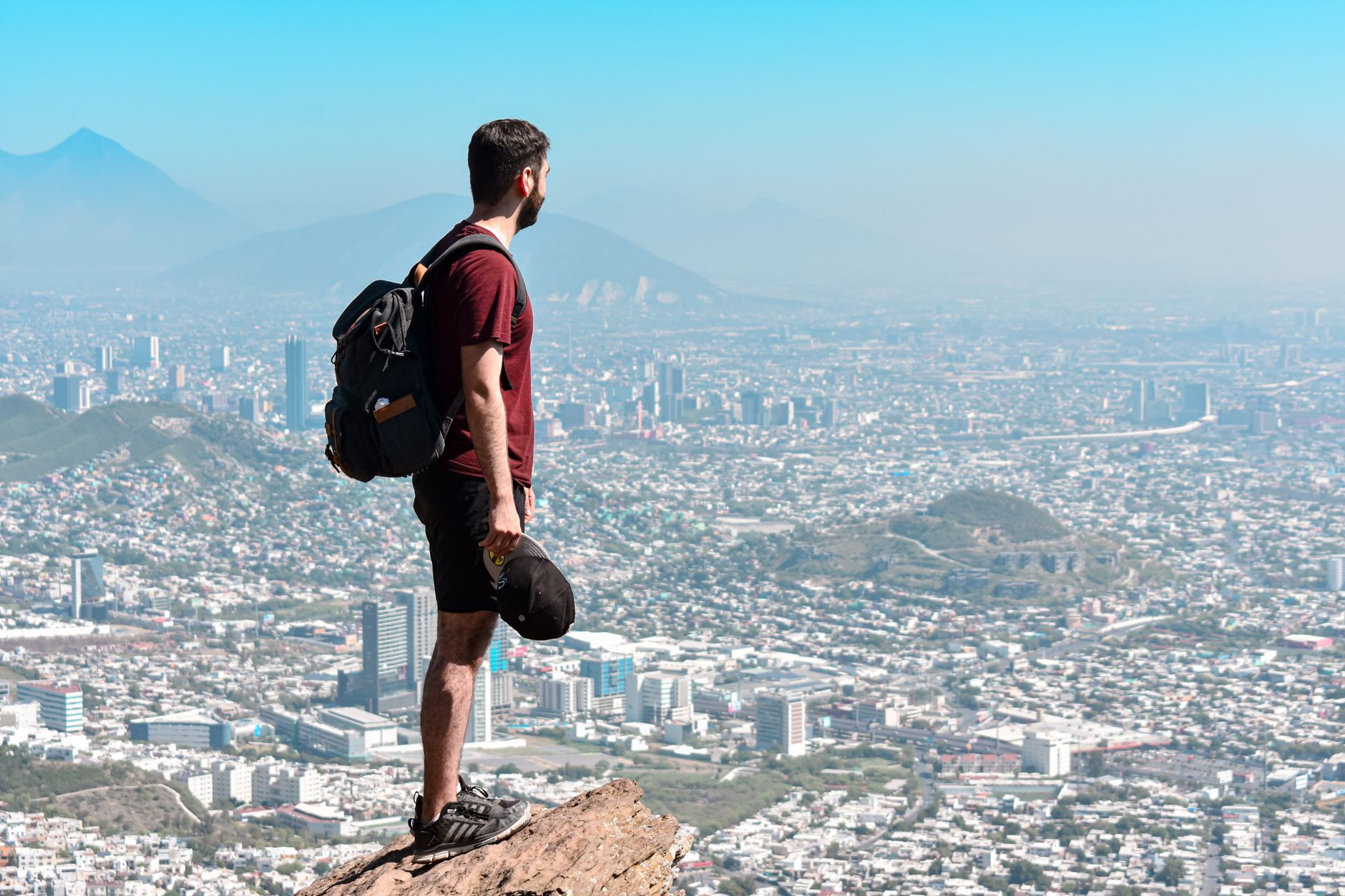 Podróżnik z plecakiem na skale z widokiem na miasto Monterrey Podróżnik z plecakiem na skale z widokiem na miasto Monterrey