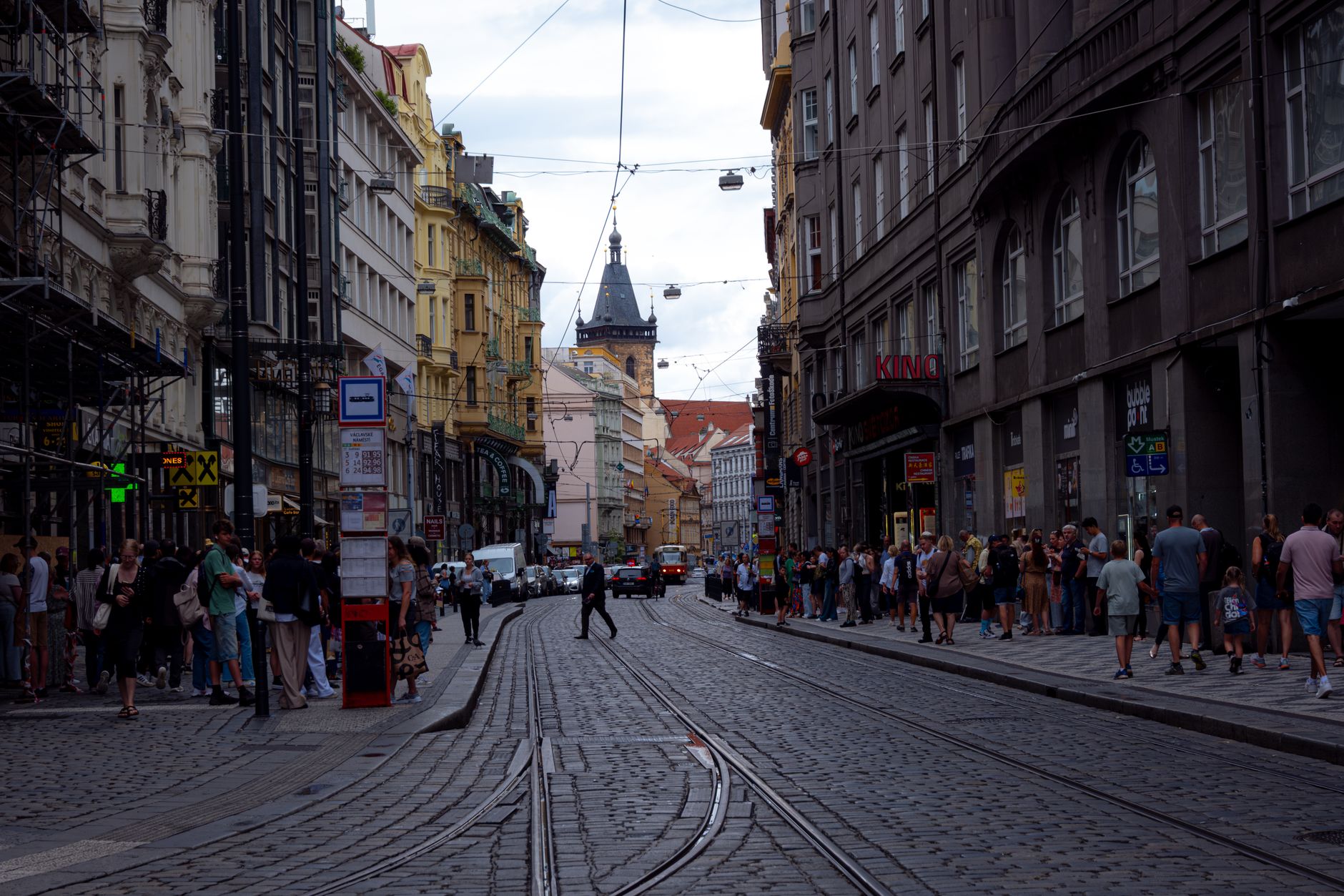 Ruchliwa ulica w Pradze z torami tramwajowymi i zabytkowymi kamienicami