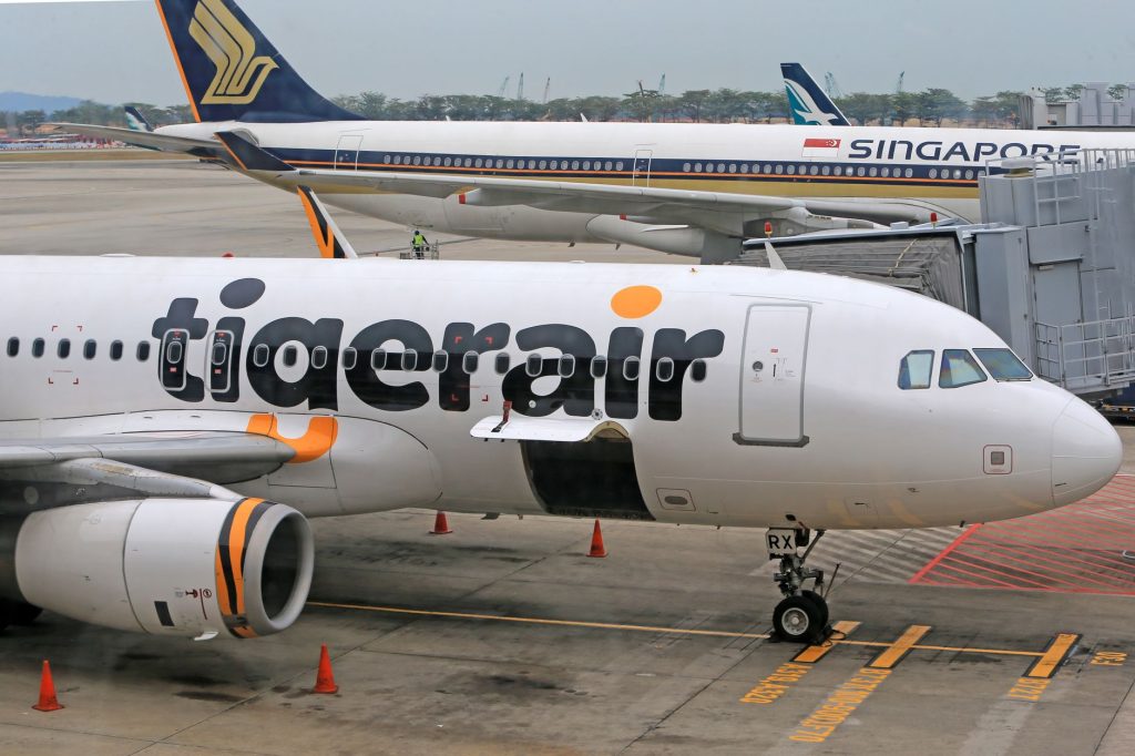 Samolot Tigerair przy bramce lotniskowej, w tle Singapore Airlines